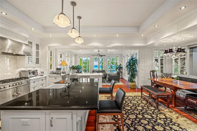 a kitchen with stainless steel appliances granite countertop a stove a sink a dining table chairs and view of living room