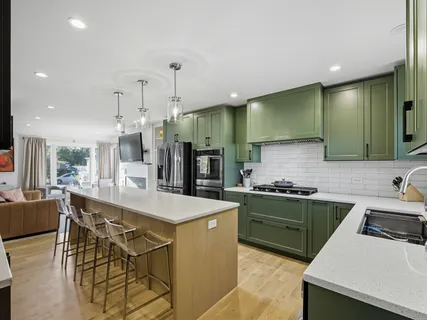 a large kitchen with stainless steel appliances a stove a sink a oven a dining table and chairs