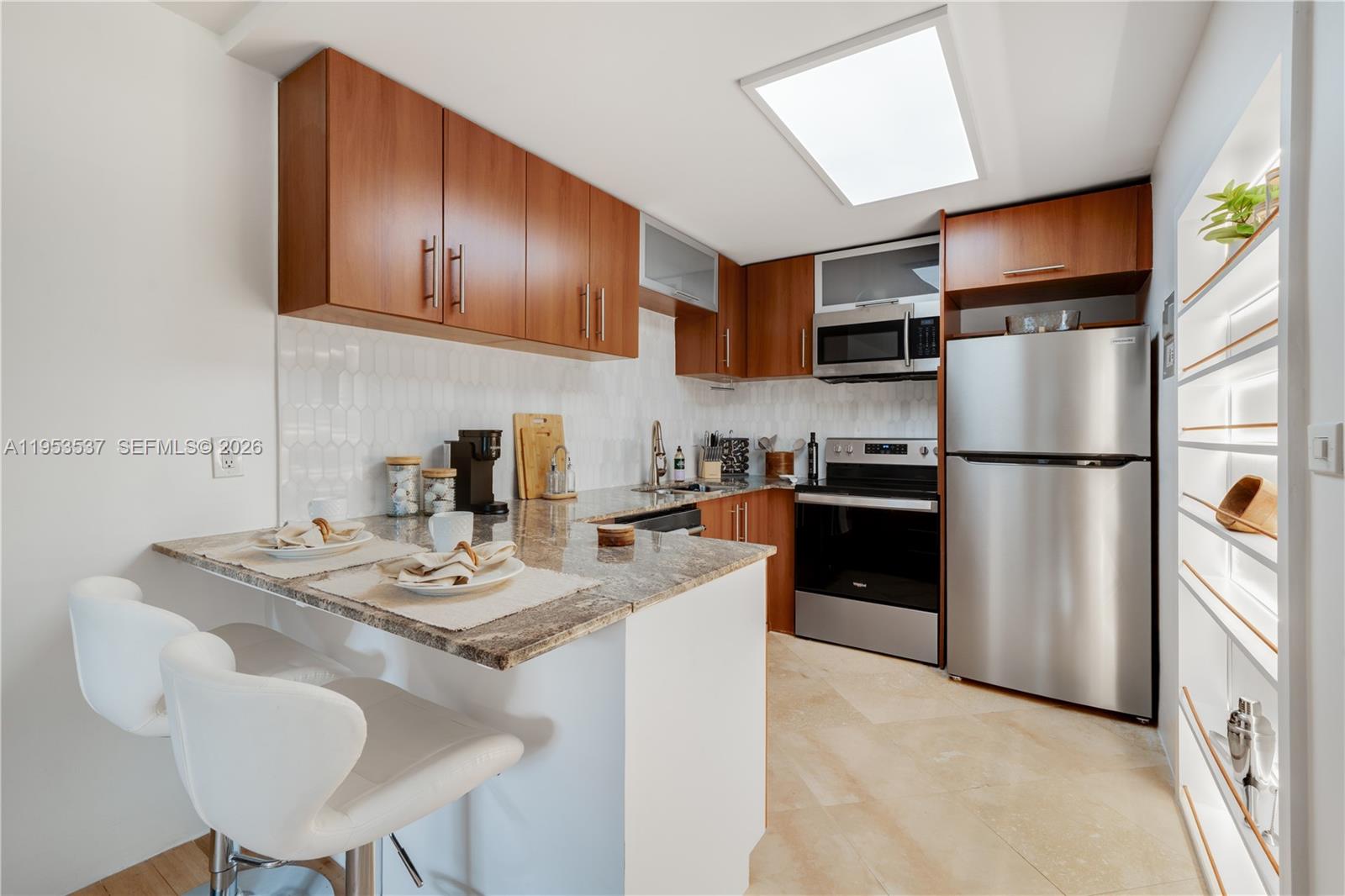 651 Northeast 60th Street, Unit 25 Miami, FL 33137 - Photo 2 of 23 a kitchen with stainless steel appliances granite countertop a refrigerator a sink dishwasher a stove a dining table and chairs with wooden floor