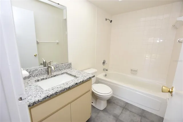 a bathroom with a granite countertop sink a toilet and bathtub