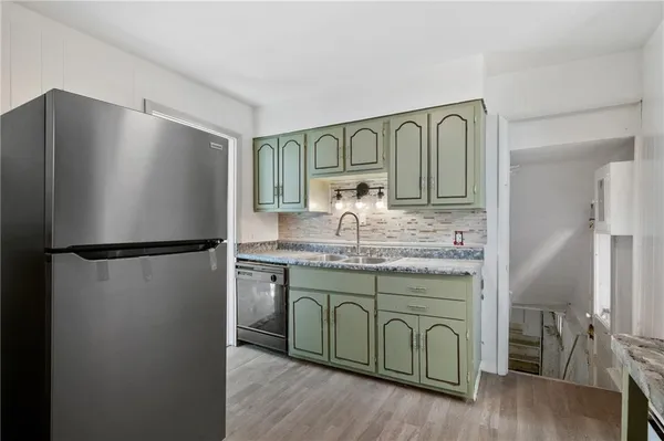 a kitchen with stainless steel appliances granite countertop a refrigerator a stove and a sink