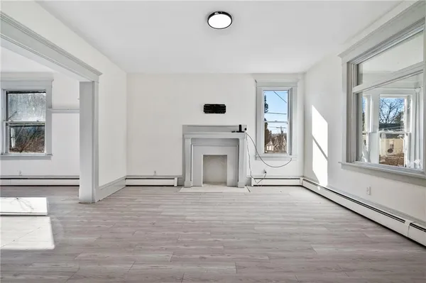 an empty room with wooden floor and a fireplace
