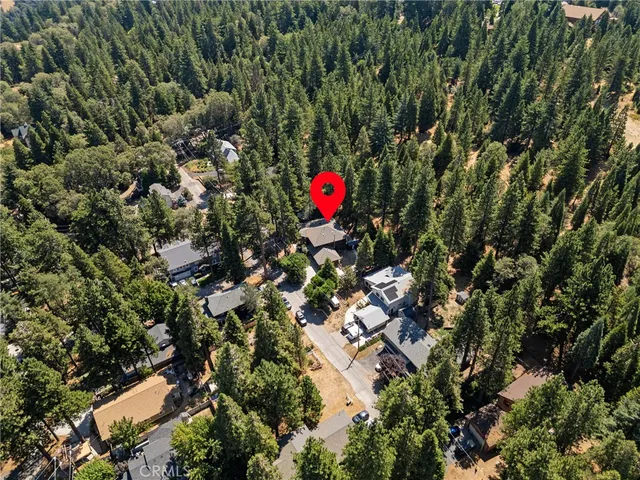 an aerial view of residential house with outdoor space and trees all around