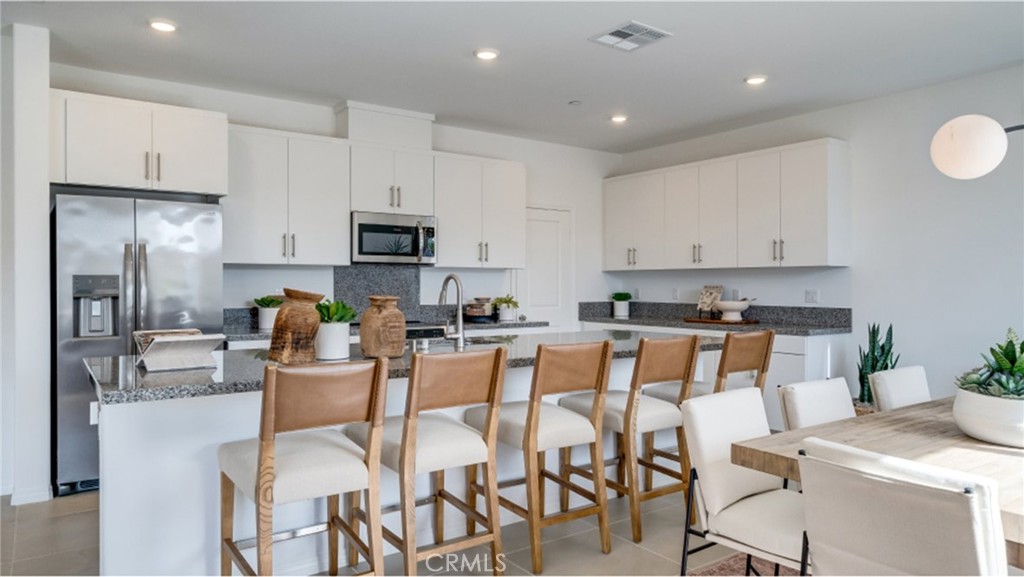 2335 Rivendell Road Perris, CA 92570 - Photo 1 of 1 a kitchen with stainless steel appliances granite countertop a stove top oven a refrigerator a kitchen island and chairs with white cabinets