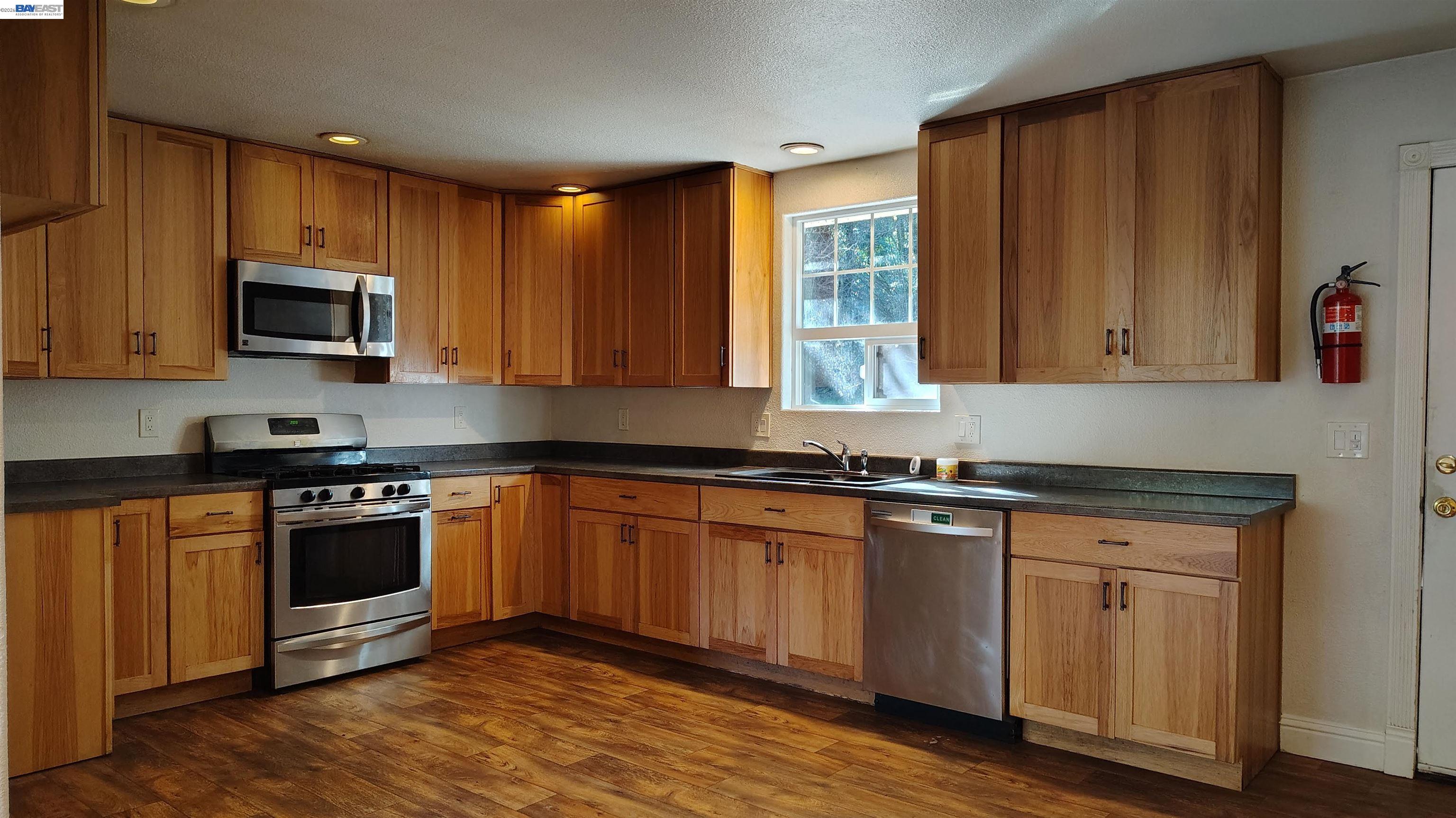 28440 Ryan Creek Road Willits, CA 95490 - Photo 9 of 22 a kitchen with granite countertop wooden cabinets stainless steel appliances and a window