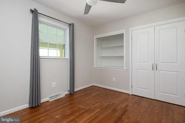 an empty room with wooden floor fireplace and windows