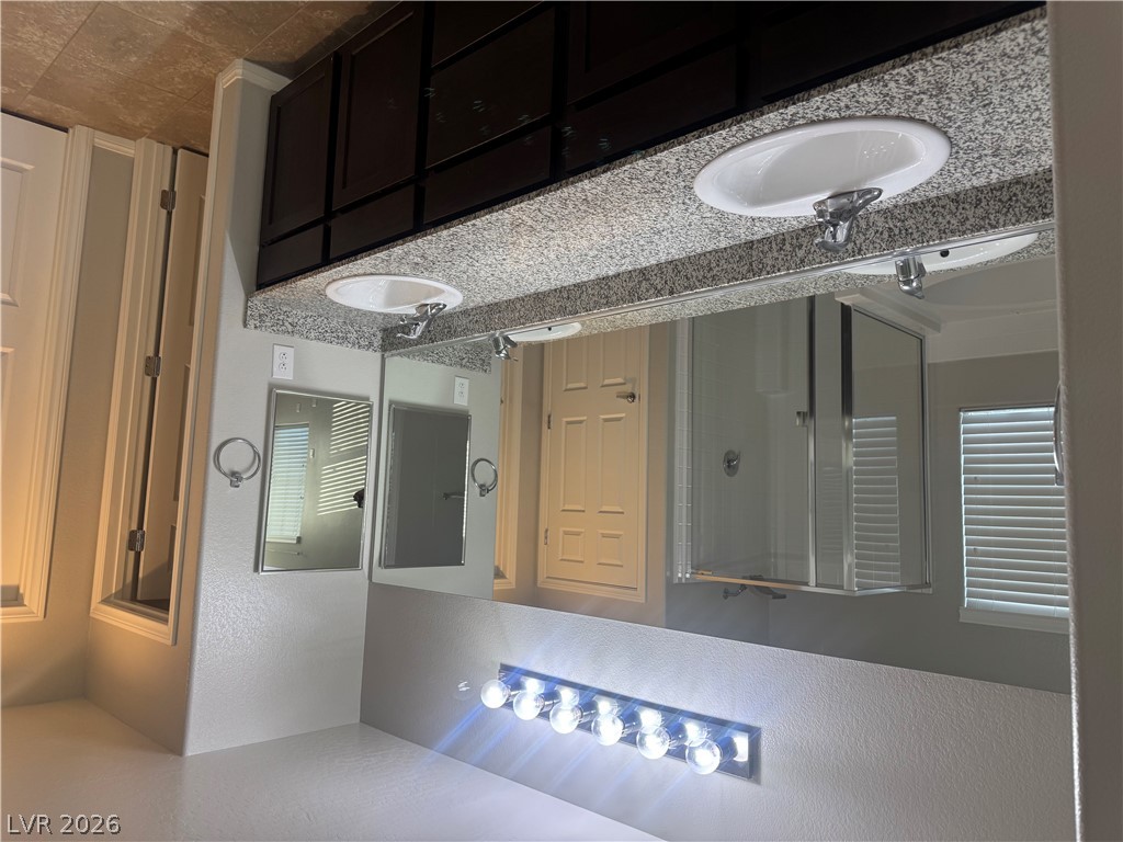 55 Canopus Ridge Way Las Vegas, NV 89183 - Photo 26 of 53 A spacious double vanity features granite countertops and dark wood cabinetry.