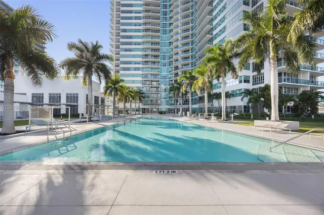 a view of a swimming pool with a lawn chairs and palm trees
