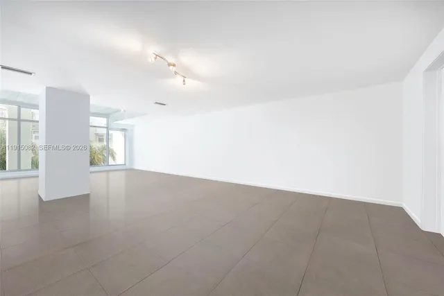 an empty room with chandelier fan and windows