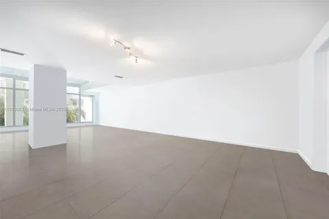 an empty room with chandelier fan and windows