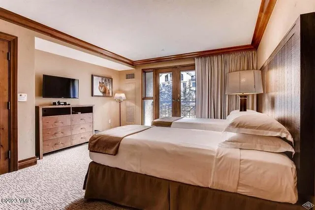 a spacious bedroom with a bed and a flat screen tv