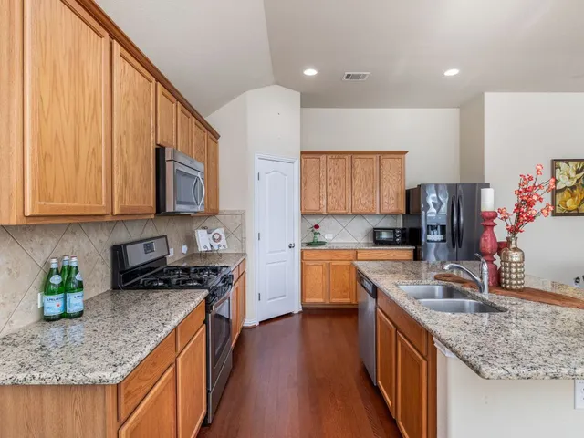 a kitchen with stainless steel appliances granite countertop a sink stove and refrigerator