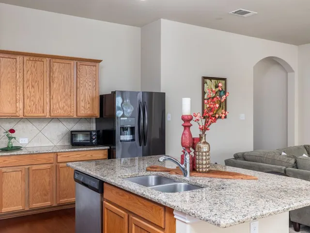 a kitchen with stainless steel appliances granite countertop a sink and a refrigerator