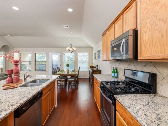 a kitchen with stainless steel appliances granite countertop a stove top oven a sink dishwasher and cabinets with wooden floor