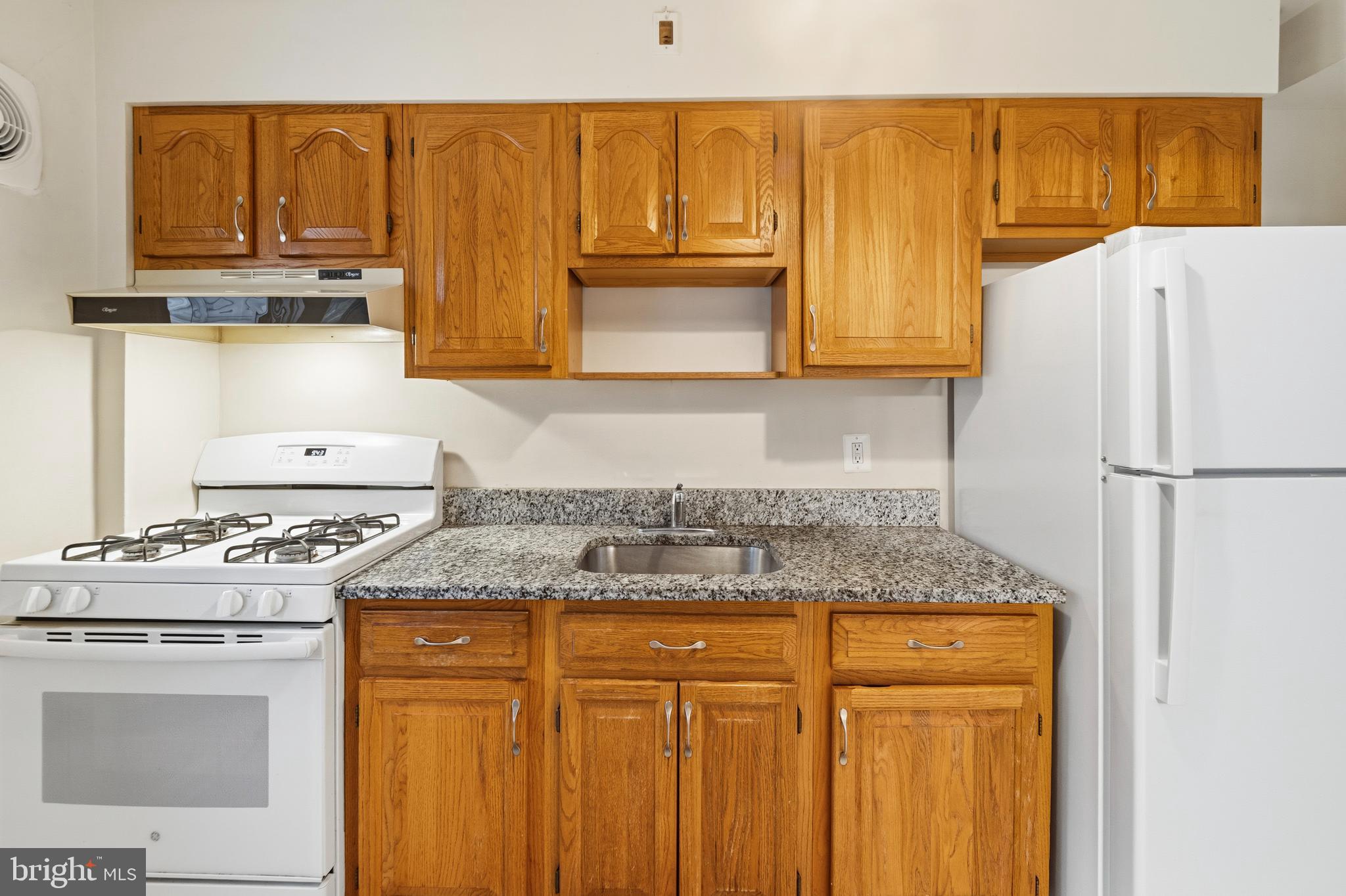 166 Cherrydell Road Baltimore, MD 21228 - Photo 15 of 24 a kitchen with granite countertop wood cabinets and white appliances