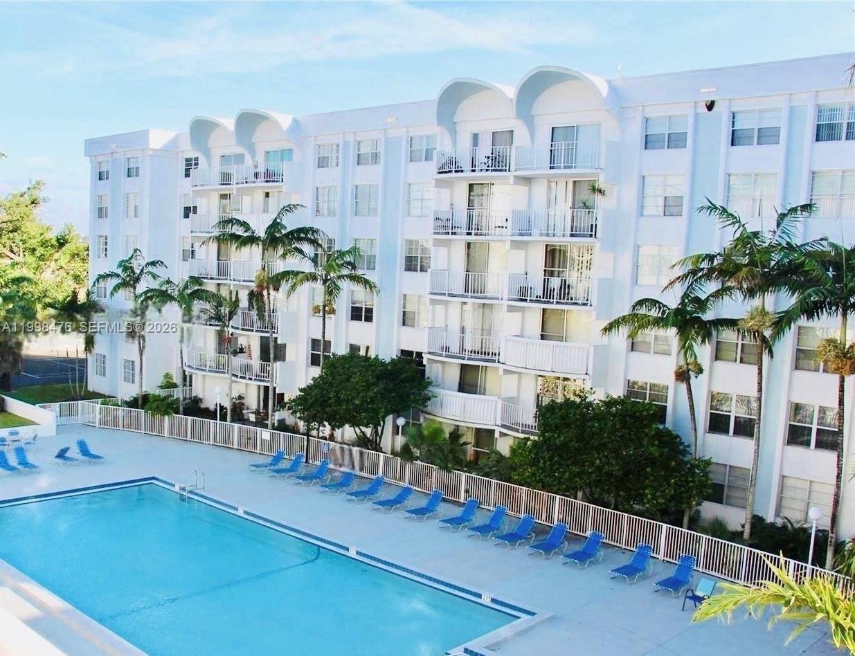 494 Northwest 165th Street, Unit C601 Miami, FL 33169 - Photo 2 of 22 a picture of a building with potted plants and large trees
