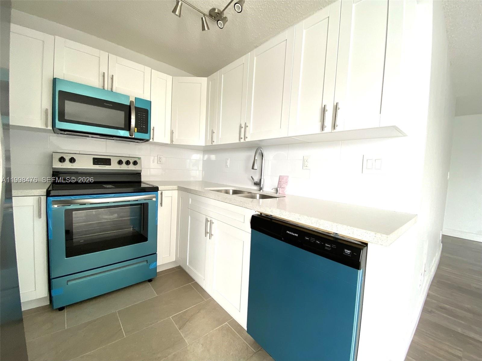 494 Northwest 165th Street, Unit C601 Miami, FL 33169 - Photo 9 of 22 a kitchen with a stove microwave and sink