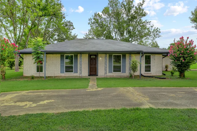 a brick house next to a yard with large trees