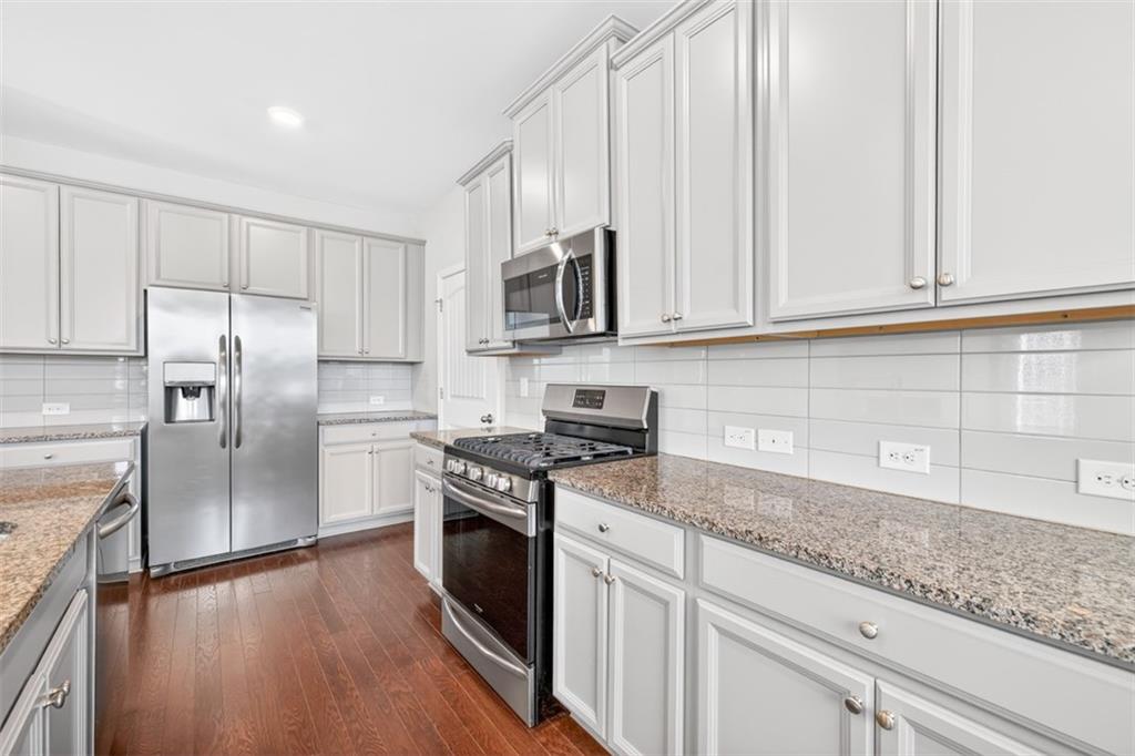 2405 Boxwalking Court Cumming, GA 30040 - Photo 11 of 54 a kitchen with stainless steel appliances granite countertop a stove a sink and a refrigerator