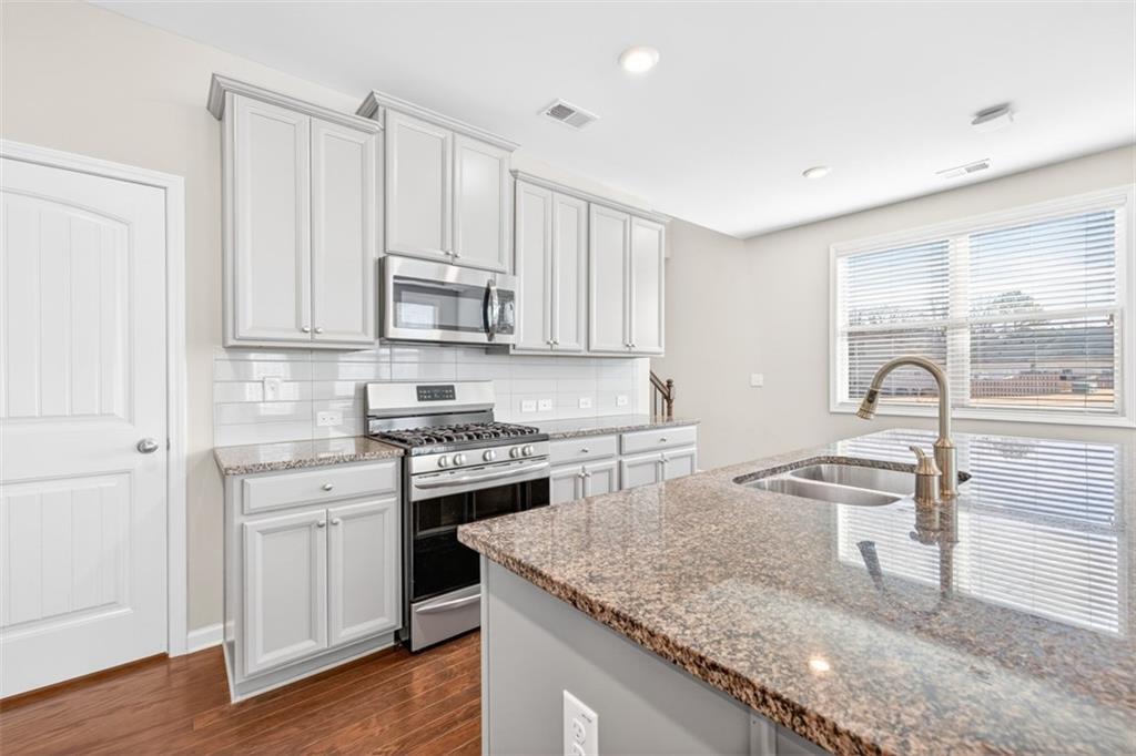 2405 Boxwalking Court Cumming, GA 30040 - Photo 13 of 54 a kitchen with stainless steel appliances granite countertop a stove a sink and a microwave