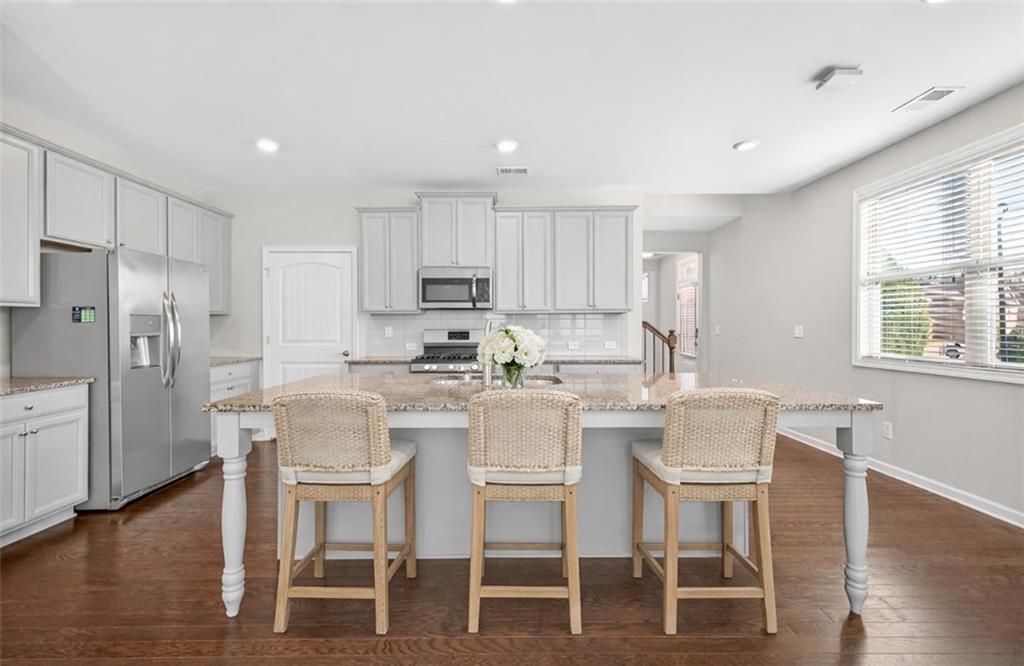 2405 Boxwalking Court Cumming, GA 30040 - Photo 9 of 54 a kitchen with a dining table chairs wooden floor cabinets appliances and a window