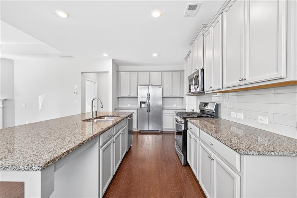 2405 Boxwalking Court Cumming, GA 30040 - Photo 10 of 54 a kitchen with stainless steel appliances granite countertop a sink stove and refrigerator