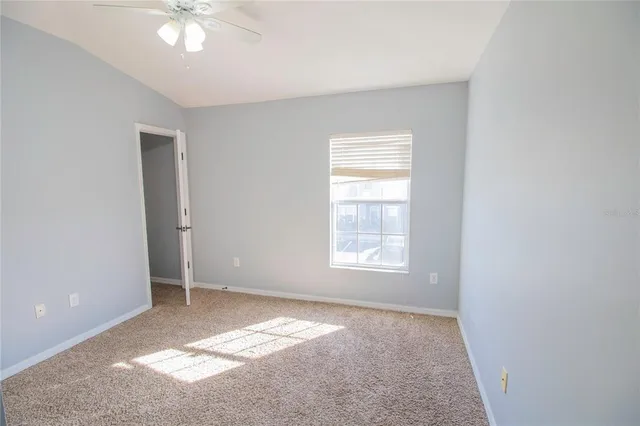 an empty room with a chandelier fan and windows