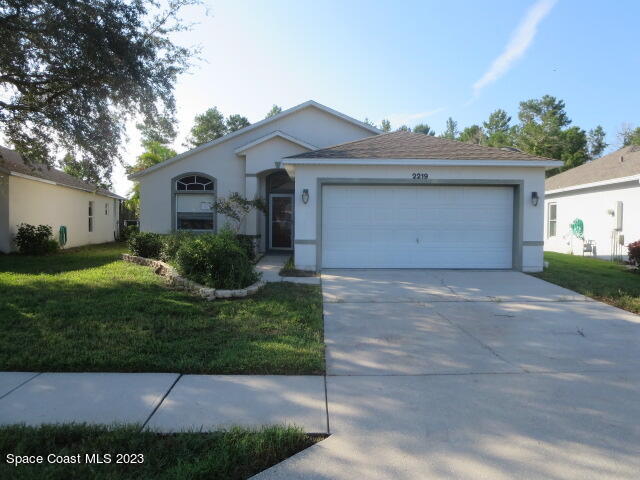 2219 Spring Creek Circle Palm Bay, FL 32905 - Photo 2 of 13 a front view of a house with a garden and plants