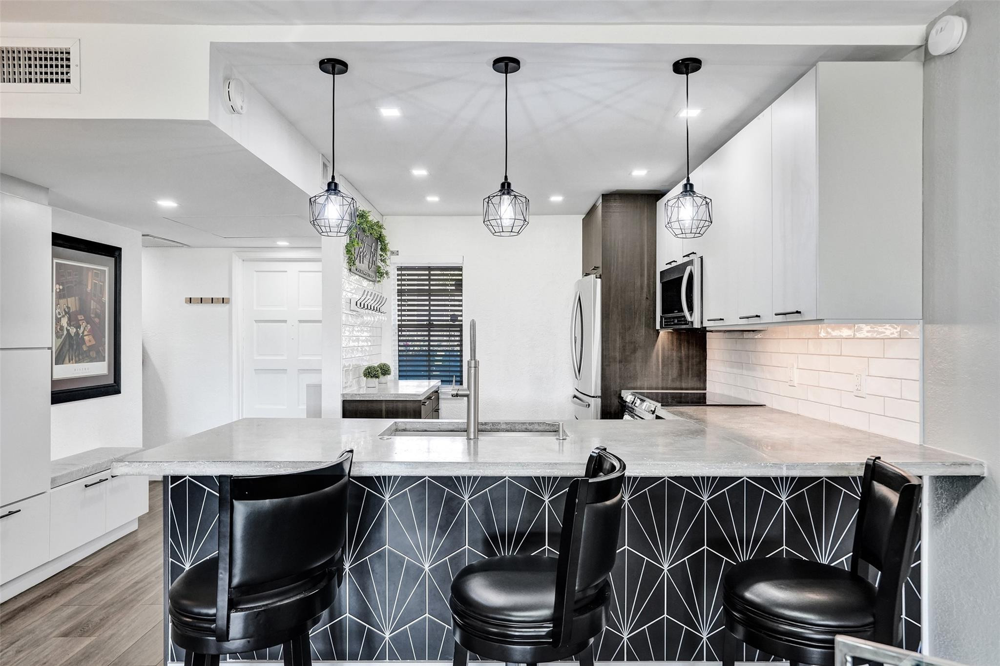 3001 South Course Drive, Unit 107 Pompano Beach, FL 33069 - Photo 17 of 47 a kitchen with stainless steel appliances kitchen island granite countertop a table chairs in it and wooden floors