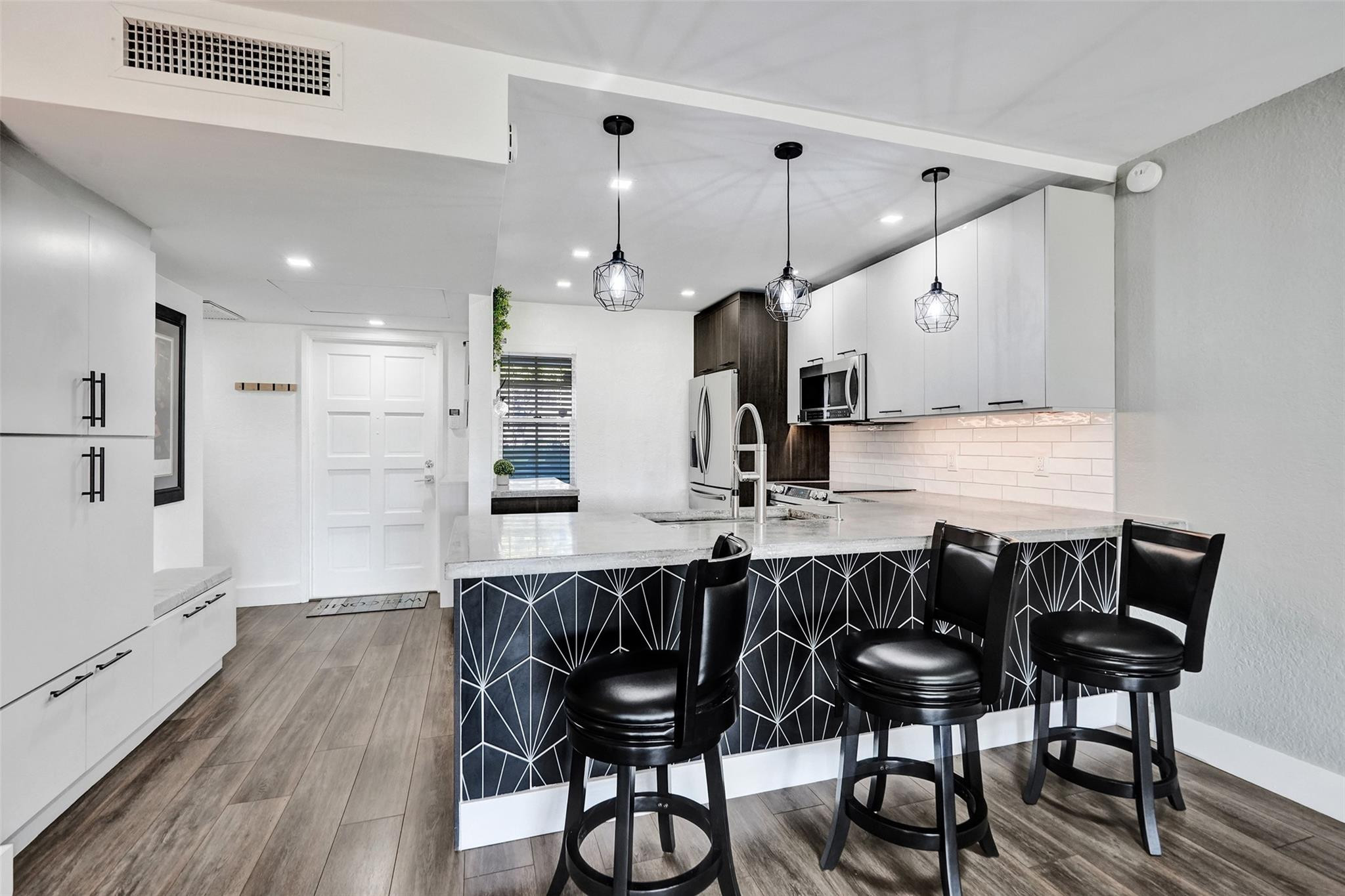 3001 South Course Drive, Unit 107 Pompano Beach, FL 33069 - Photo 2 of 47 a kitchen with stainless steel appliances kitchen island granite countertop a table chairs sink and cabinets