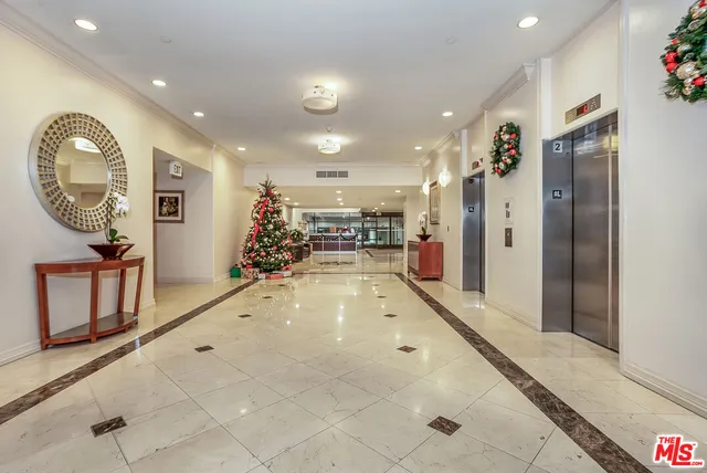 a front view of a building with lot of cars and trees