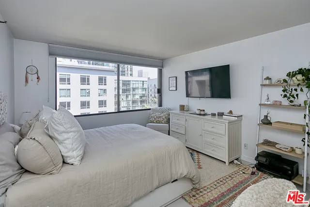 a bedroom with a bed and a flat tv screen on dresser