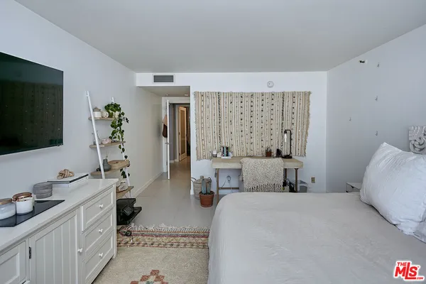a bedroom with a large bed and a flat tv screen on dresser
