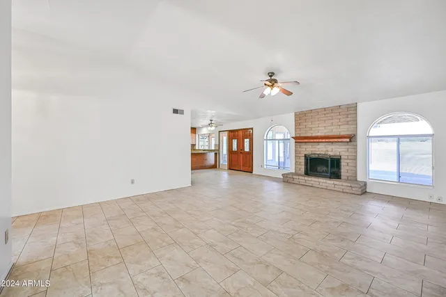 an empty room with windows and fireplace