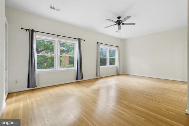 a view of an empty room with a window and wooden floor