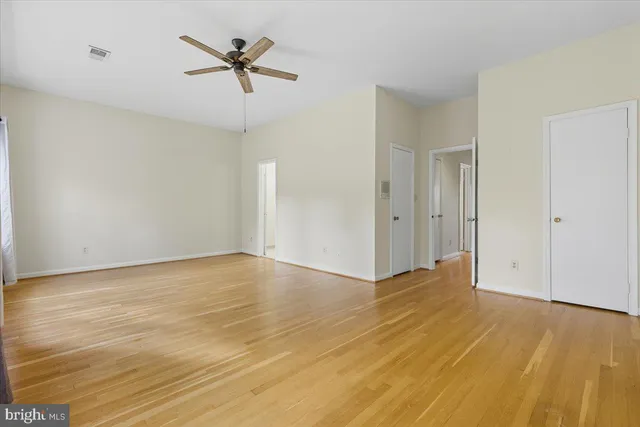 an empty room with wooden floor and ceiling fan