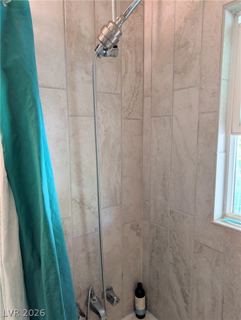 102 Rowan Drive Caliente, NV 89008 - Photo 17 of 28 A well-lit shower area features neutral-toned tiled walls and a bright window.