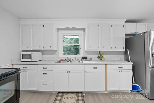 a kitchen with white cabinets and sink