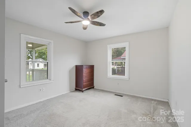 an empty room with windows and ceiling fan