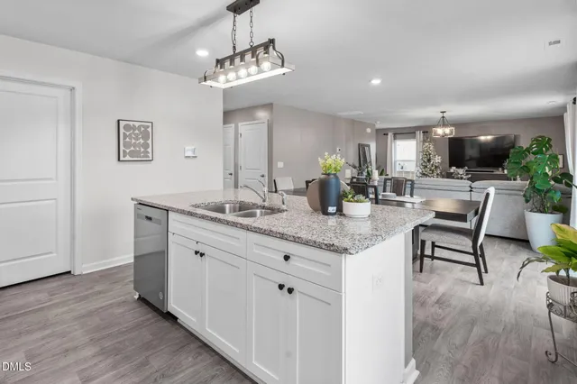 a room with stainless steel appliances granite countertop furniture a fireplace a window and a chandelier