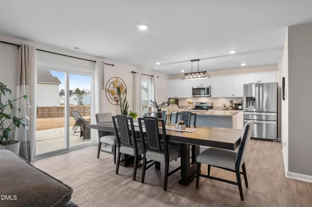 a kitchen with stainless steel appliances granite countertop a sink dishwasher a microwave oven a refrigerator with white cabinets and wooden floor