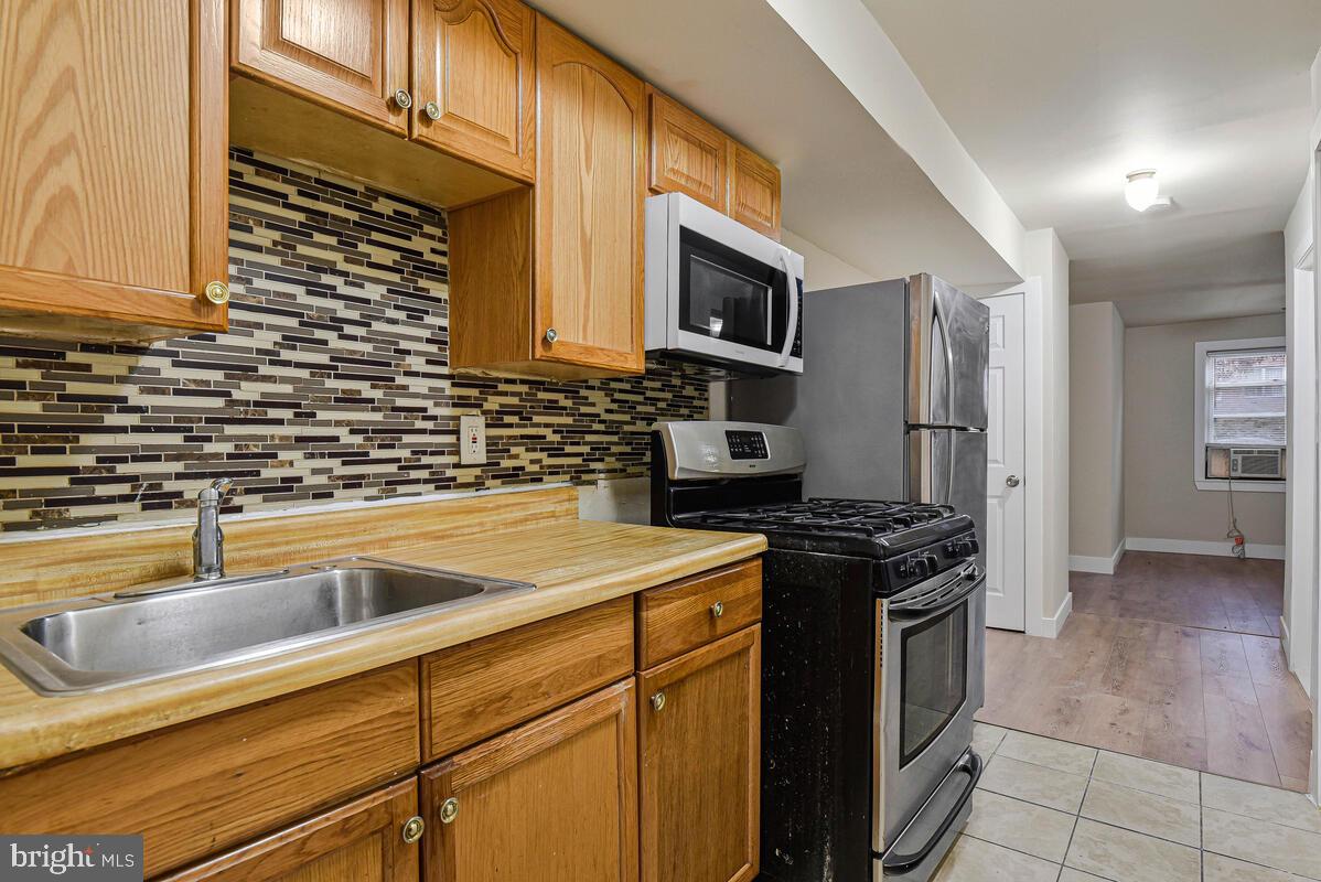 3427 B Street Southeast, Unit 1 Washington, DC 20019 - Photo 13 of 17 a kitchen with stainless steel appliances granite countertop a stove a sink and a microwave
