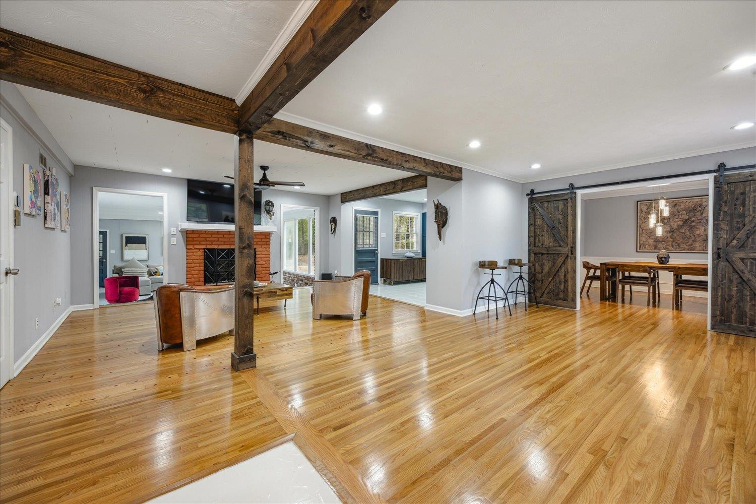 3076 Laurencekirk Road Memphis, TN 38128 - Photo 5 of 23 Living room with beamed ceiling, ceiling fan, a fireplace, light hardwood / wood-style flooring, and a barn door