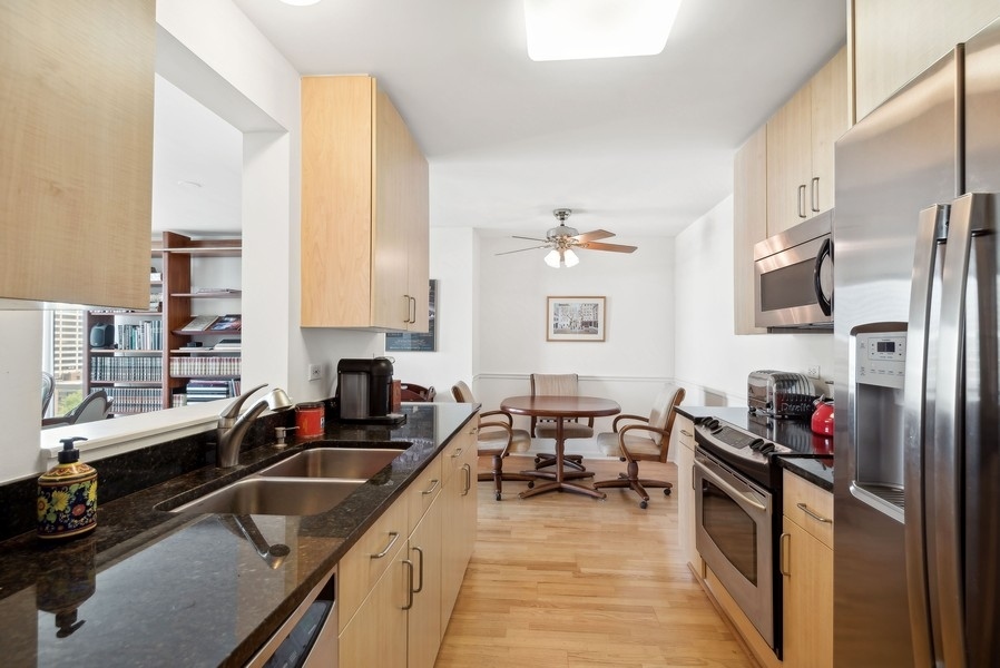 1640 Maple Avenue, Unit 1107 Evanston, IL 60201 - Photo 6 of 28 a kitchen with stainless steel appliances granite countertop a sink dishwasher stove refrigerator and cabinets with wooden floor