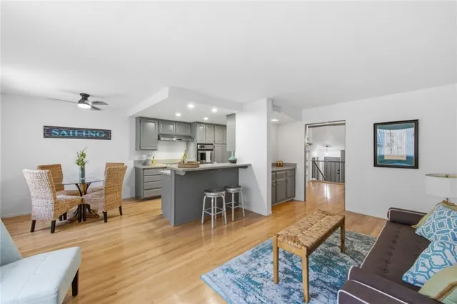 a living room with furniture kitchen view and a wooden floor