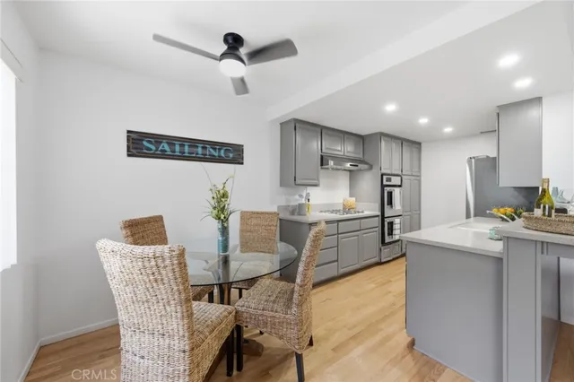 a kitchen with stainless steel appliances kitchen island granite countertop a table chairs and a refrigerator