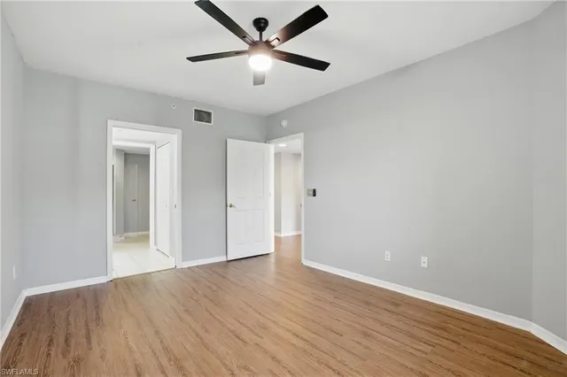 an empty room with wooden floor and a ceiling fan