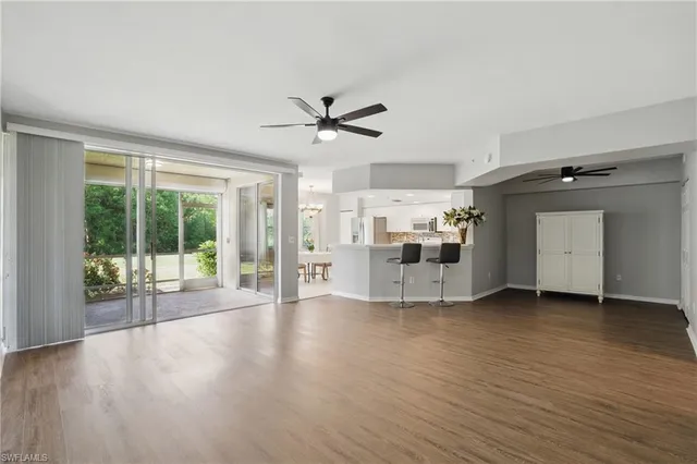 a view of a big room with wooden floor a ceiling fan and windows