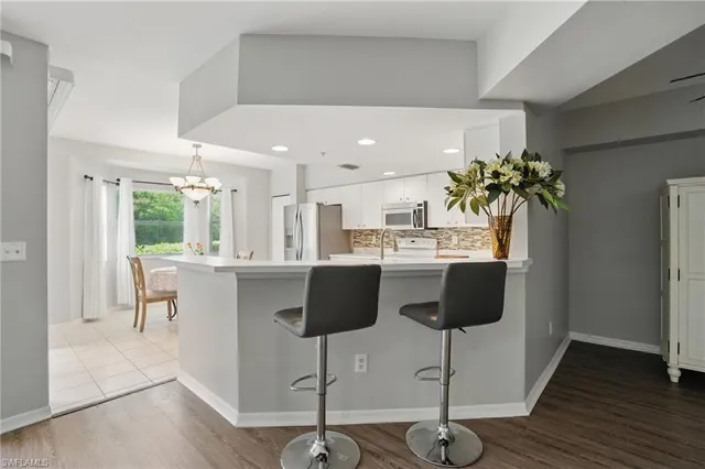 a kitchen with stainless steel appliances kitchen island granite countertop a table chairs and a refrigerator