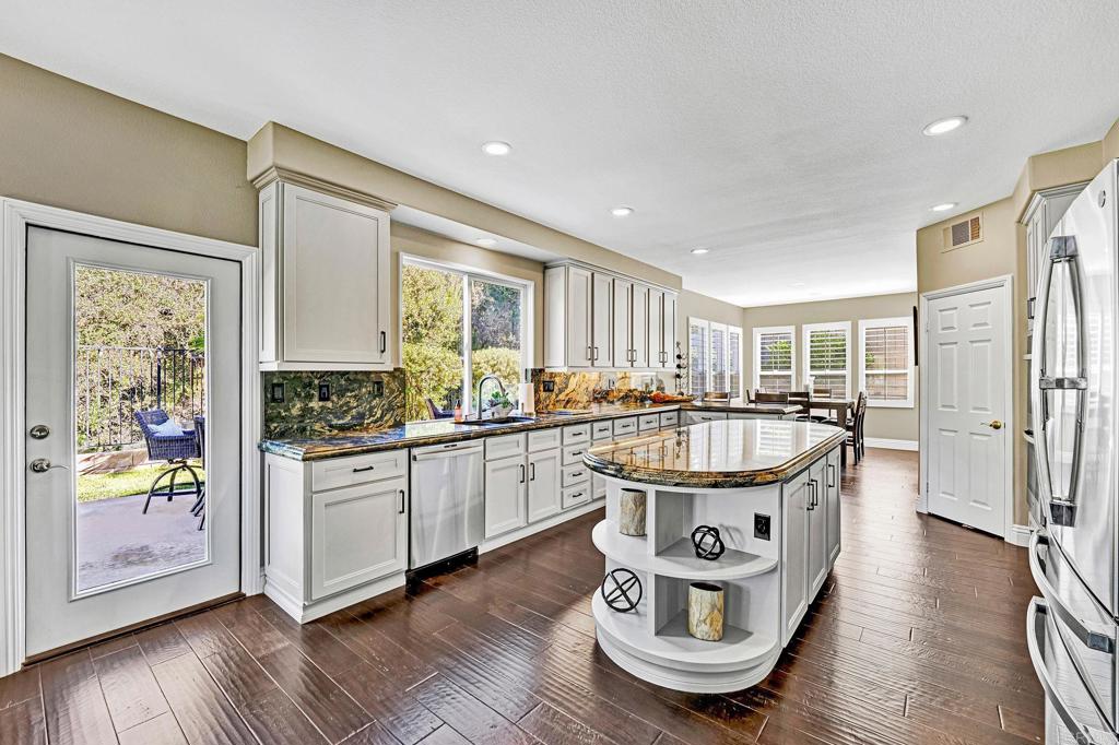 1463 Belmont Park Road Oceanside, CA 92057 - Photo 14 of 50 a kitchen with stainless steel appliances granite countertop a refrigerator a stove and a cabinets with wooden floor